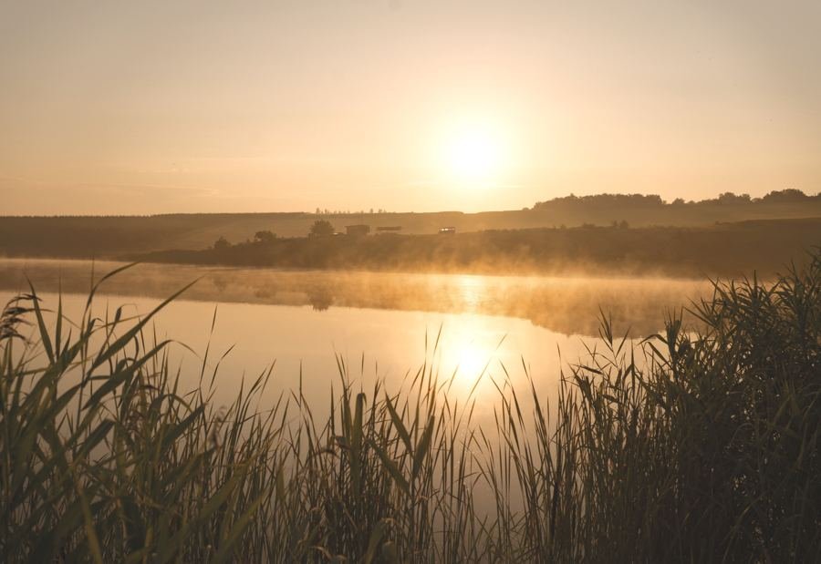 Solopgang over vann, tidlig morgen